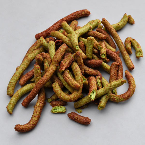 Churros de nopal verdes con cobertura rojiza de adobo, apilados sobre fondo gris.