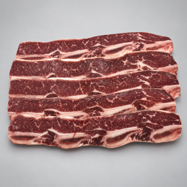 Cinco tiras de Short Rib Choice con hueso y marmoleo visible sobre fondo gris.