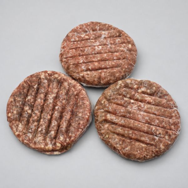 Tres hamburguesas de res Angus 80/20 con surcos en la superficie sobre fondo gris.